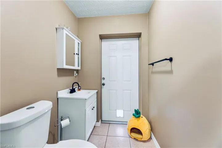 Bathroom featuring tile flooring, vanity, toilet, and a textured ceiling