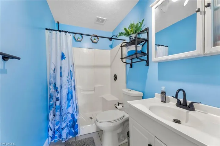 Full bathroom featuring a textured ceiling, shower / bath combo, tile floors, oversized vanity, and toilet