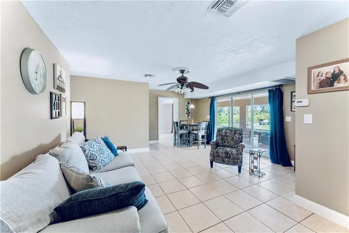 Living room with a textured ceiling, ceiling fan, and light tile floors
