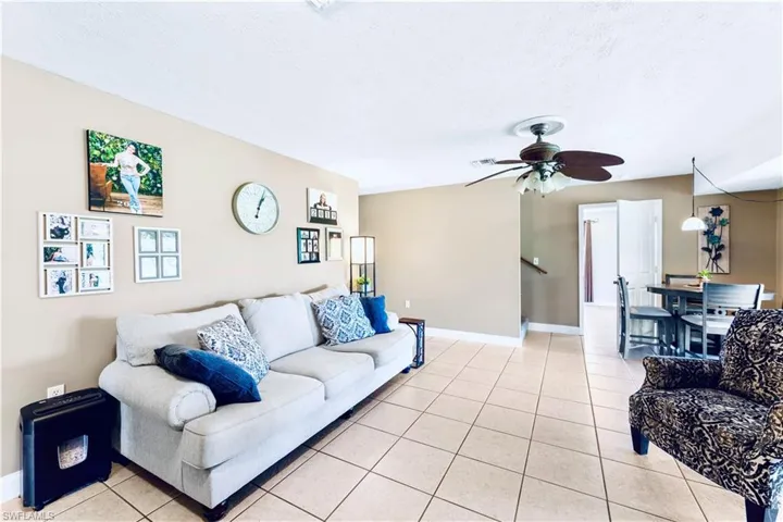 Living room with ceiling fan and light tile floors