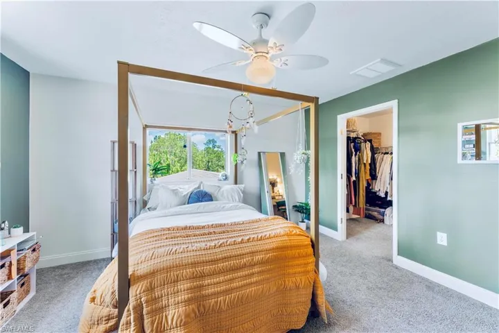 Carpeted bedroom featuring ceiling fan, a closet, and a walk in closet