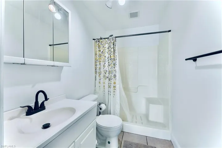 Bathroom featuring tile floors, walk in shower, oversized vanity, and toilet