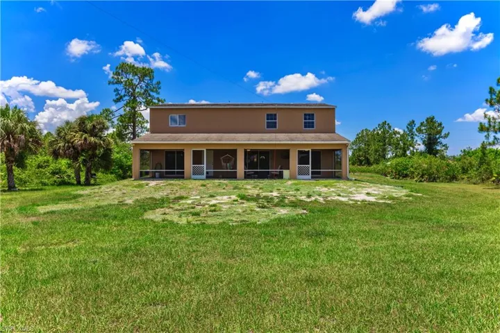 Rear view of property with a sunroom and a lawn