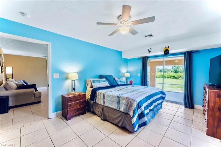Tiled bedroom featuring ceiling fan and access to exterior