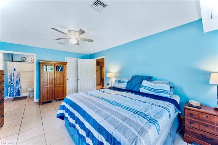 Tiled bedroom featuring ceiling fan and ensuite bathroom