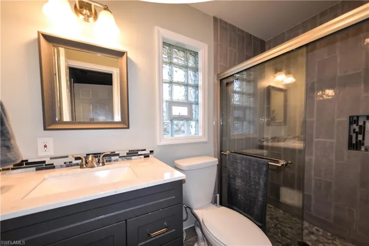 primary en-suite with porcelain tile - quartz - and glass block window