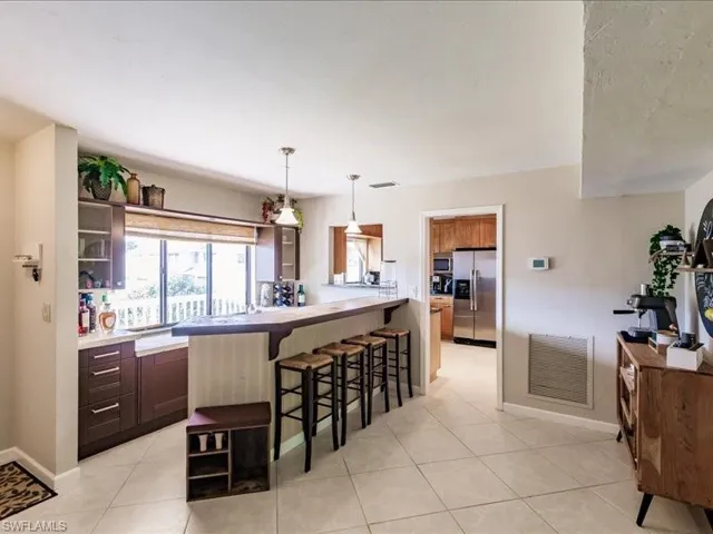Kitchen with a kitchen breakfast bar, light tile floors, pendant lighting, and appliances with stainless steel finishes