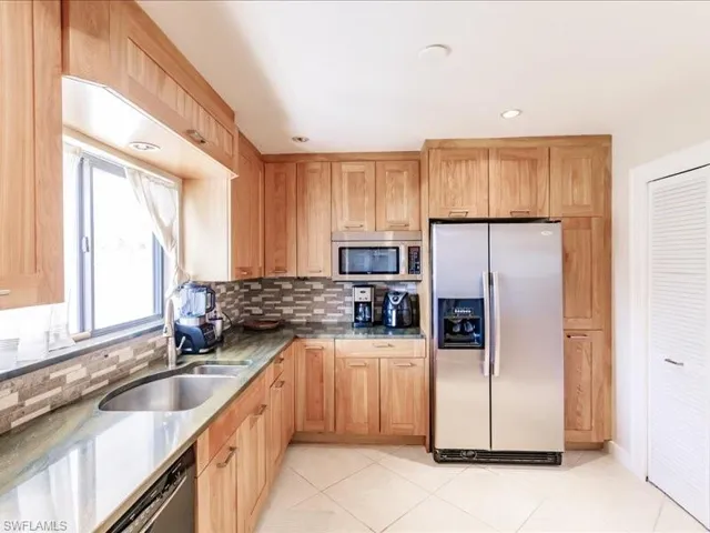 Kitchen featuring stainless steel appliances, sink, tasteful backsplash, and light tile floors