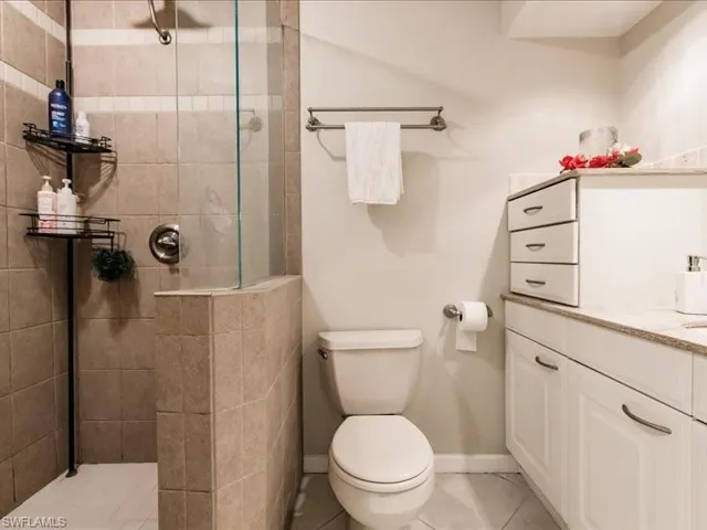 Bathroom with tile floors, a shower with door, toilet, and vanity