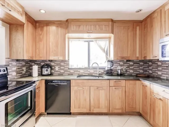 Kitchen with tasteful backsplash, dishwasher, range, light tile floors, and sink