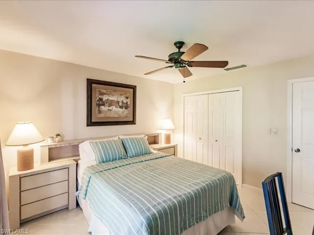 Tiled bedroom featuring ceiling fan and a closet