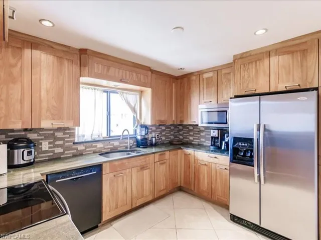 Kitchen featuring backsplash, appliances with stainless steel finishes, sink, and light tile flooring