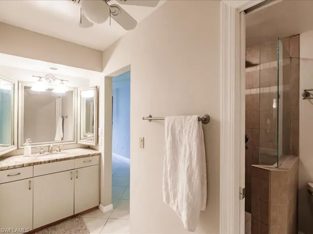 Bathroom featuring an enclosed shower, tile flooring, ceiling fan, and vanity with extensive cabinet space