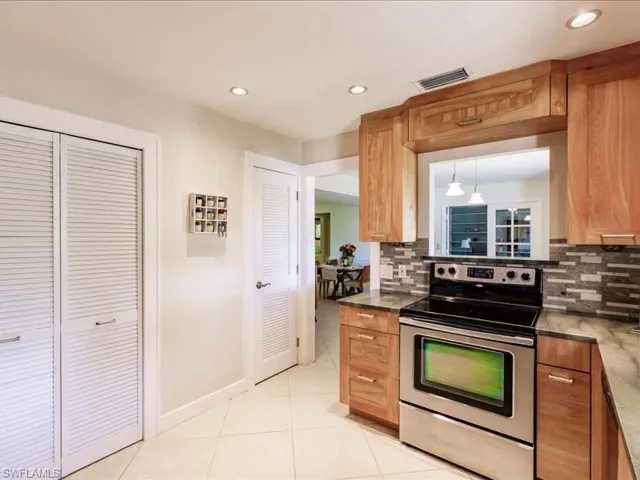 Kitchen featuring electric stove, tasteful backsplash, and light tile floors