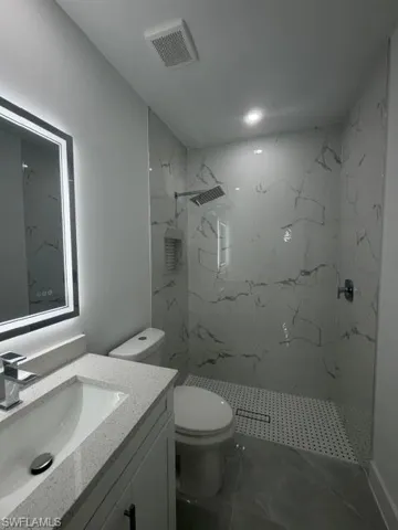 Contemporary bathroom featuring a walk-in shower with marble-look tile surround and a linear drain