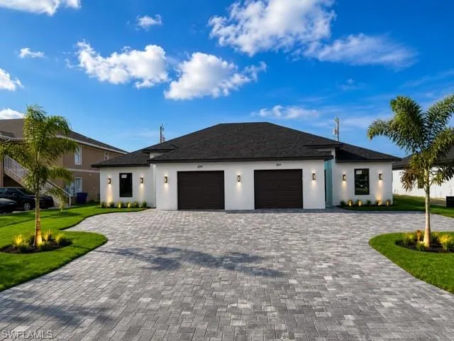 Modern duplex exterior featuring a white stucco finish and dark garage doors