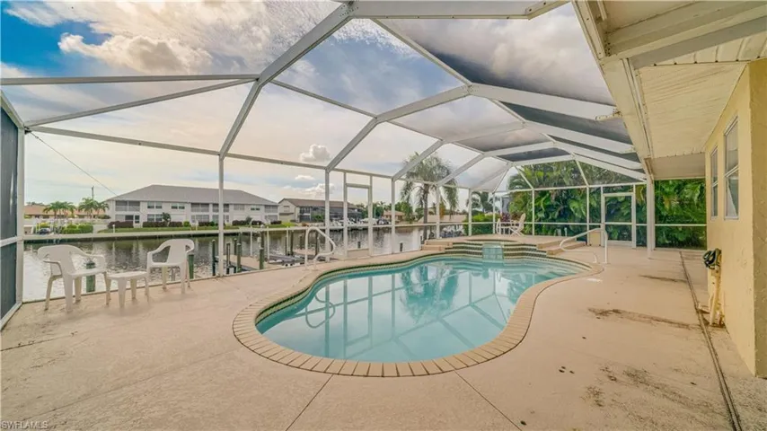 View of pool featuring a water view, a patio area, and glass enclosure