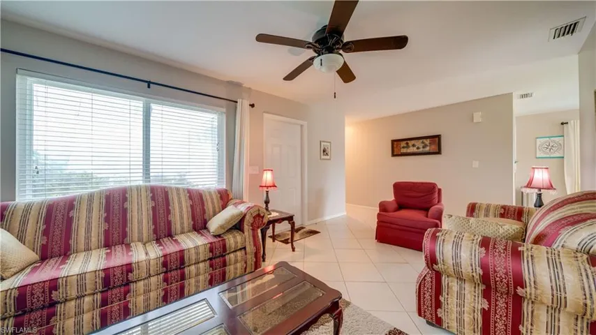 Tiled living room featuring a healthy amount of sunlight and ceiling fan