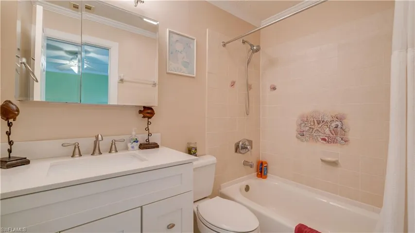 Full bathroom with shower / bath combo with shower curtain, toilet, ornamental molding, and vanity