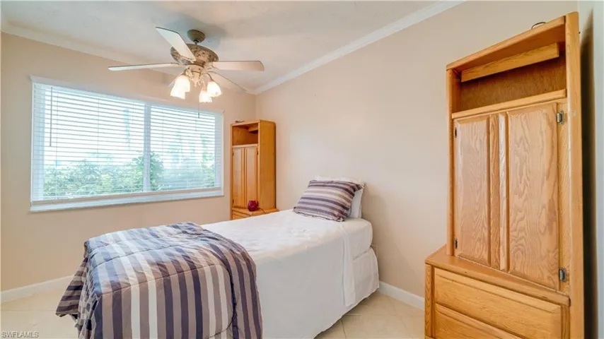Tiled bedroom featuring ornamental molding, multiple windows, and ceiling fan