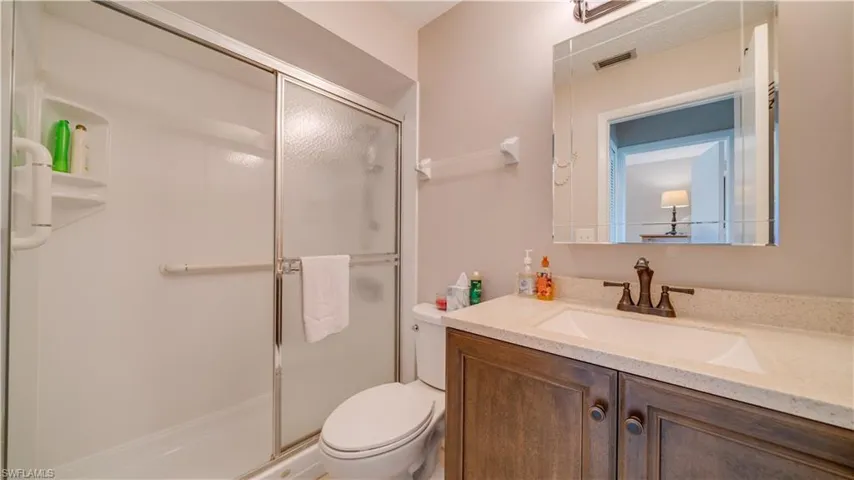 Bathroom featuring vanity, toilet, and an enclosed shower