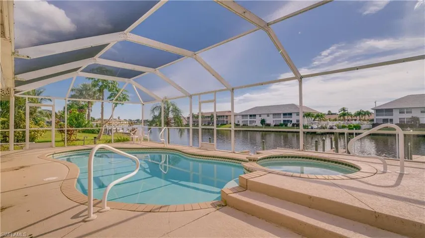 View of pool featuring a water view, a lanai, and an in ground hot tub