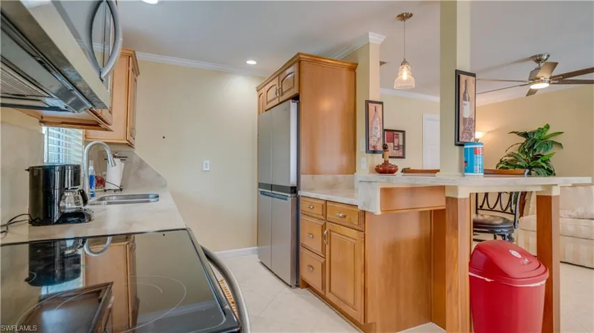 Kitchen with pendant lighting, light tile patterned floors, stainless steel appliances, sink, and ceiling fan
