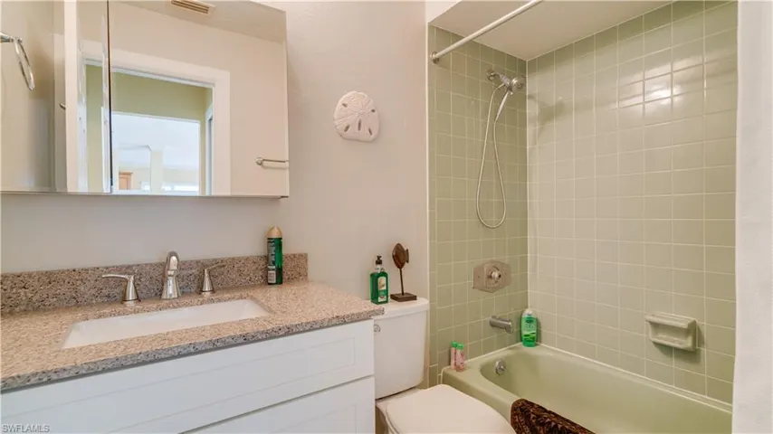 Full bathroom featuring tiled shower / bath, vanity, and toilet