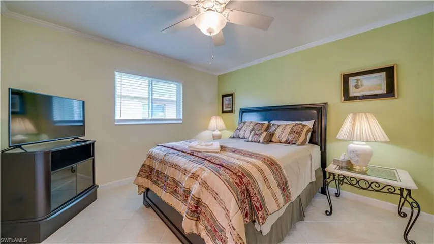Tiled bedroom with crown molding and ceiling fan