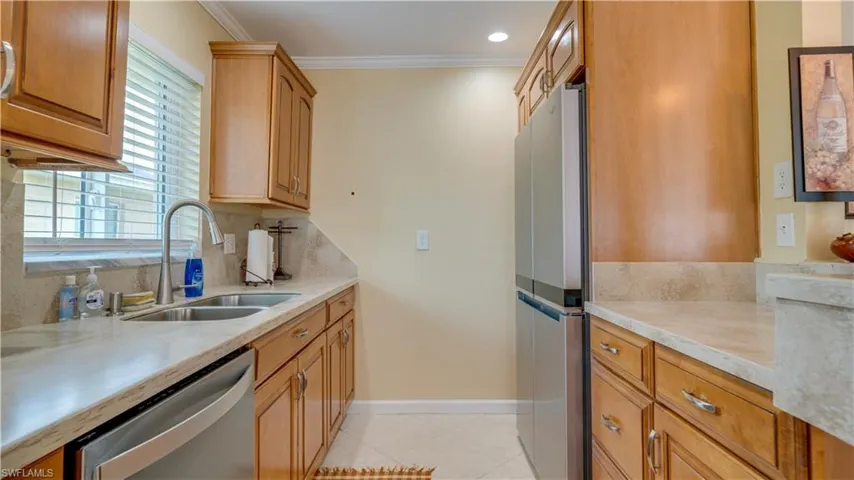 Kitchen featuring ornamental molding, tasteful backsplash, light tile patterned floors, stainless steel appliances, and sink