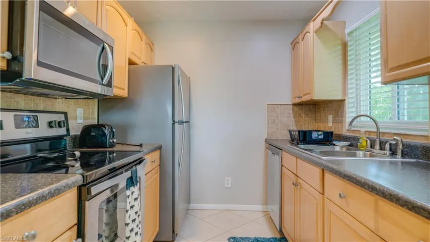 Kitchen featuring light brown cabinetry, a wealth of natural light, stainless steel appliances, and sink