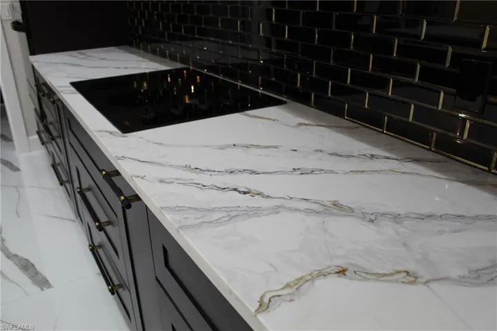 Details with black electric cooktop and decorative backsplash