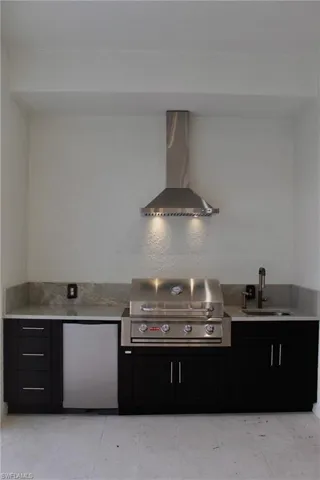 Kitchen featuring stainless steel fridge, wall chimney exhaust hood, and sink