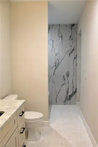 Bathroom featuring toilet, vanity, and walk in shower