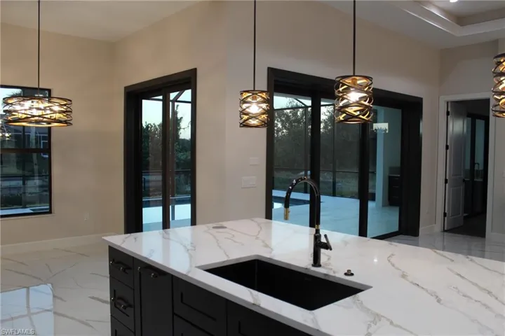 Kitchen featuring light stone counters, sink, and decorative light fixtures