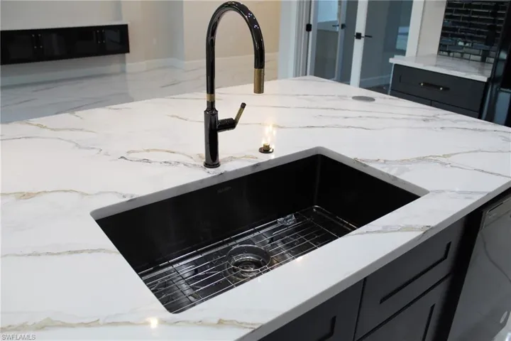 Details featuring dishwashing machine, sink, and light stone countertops
