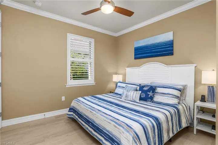 Bedroom with ornamental molding, light wood-type flooring, and ceiling fan