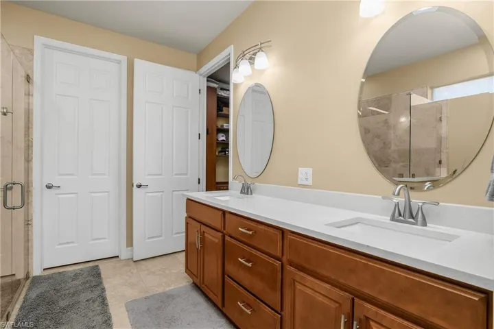 Full bath with a stall shower, double vanity, and light tile patterned floors