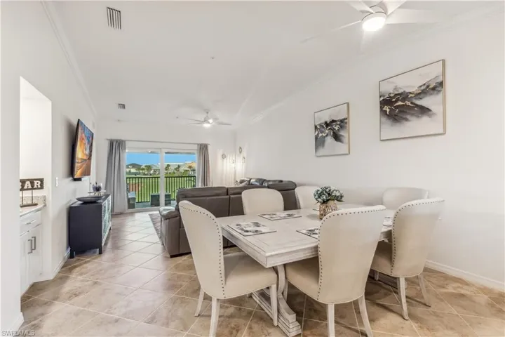 Tiled dining room featuring ceiling fan, crown molding, and lofted ceiling