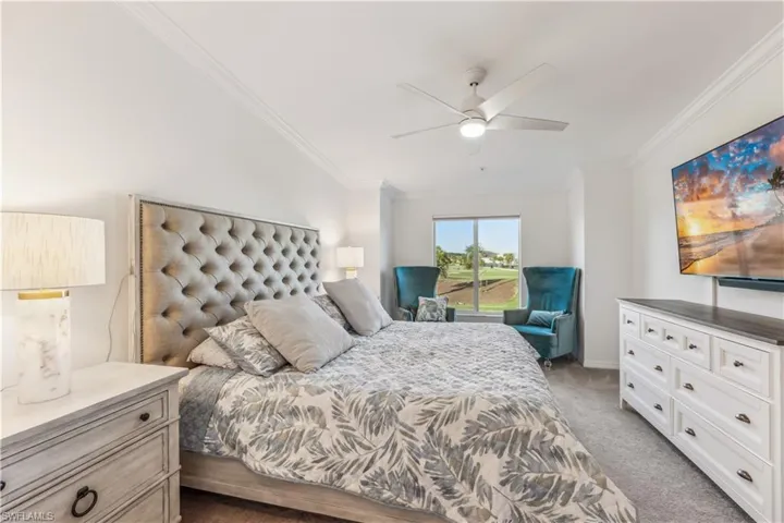 Carpeted bedroom featuring ceiling fan and crown molding