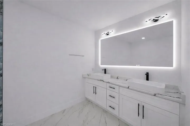 Full bathroom with double vanity and light marble finish floors