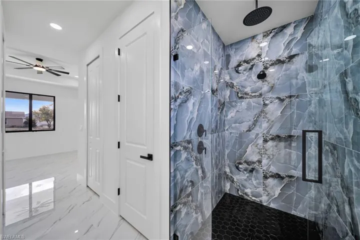 Bathroom with a marble finish shower, light marble finish flooring, a ceiling fan, and recessed lighting