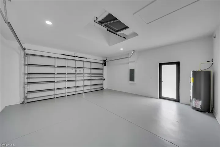 Garage with water heater, recessed lighting, and electric panel