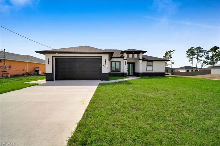 Prairie-style home featuring a front yard, concrete driveway, stucco siding, a garage, and a shingled roof