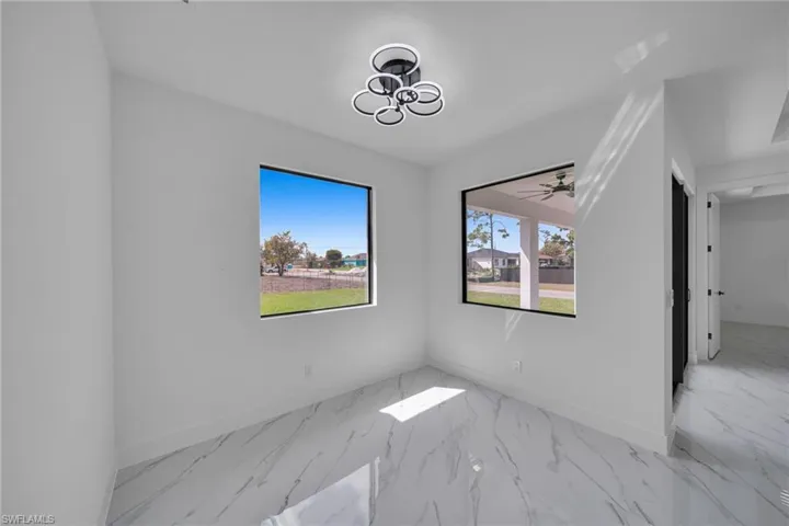 Empty room with light marble finish floors, ceiling fan, and a chandelier
