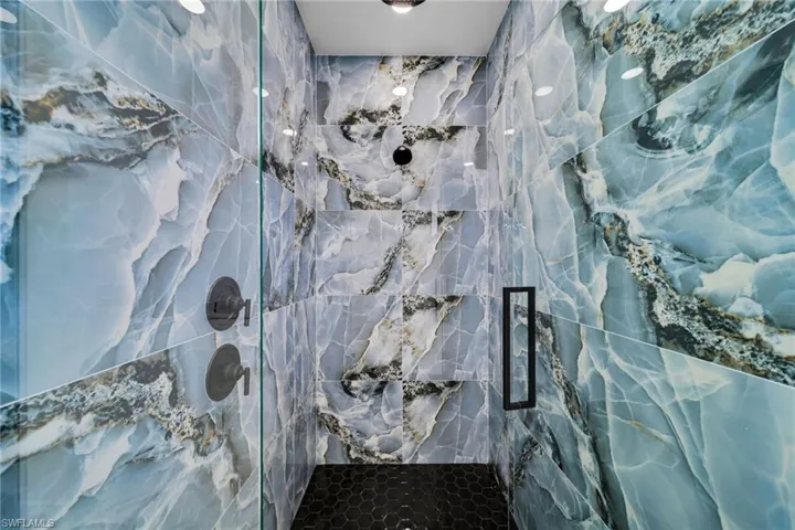 Full bath with a marble finish shower