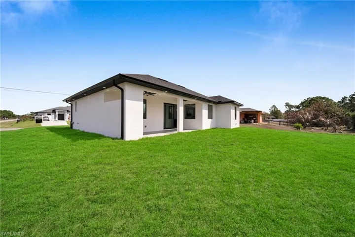 Rear view of property featuring a yard, stucco siding, a patio area, and ceiling fan