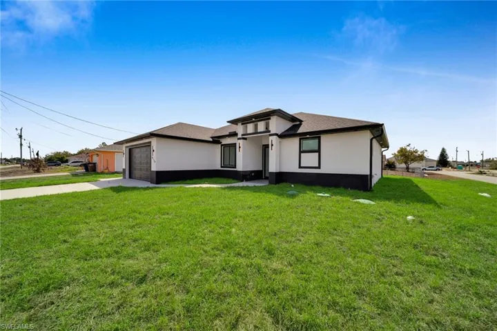 Prairie-style home featuring driveway, stucco siding, a front lawn, an attached garage, and a shingled roof