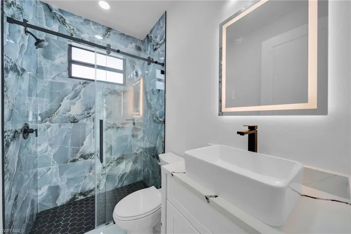 Bathroom featuring vanity and a marble finish shower