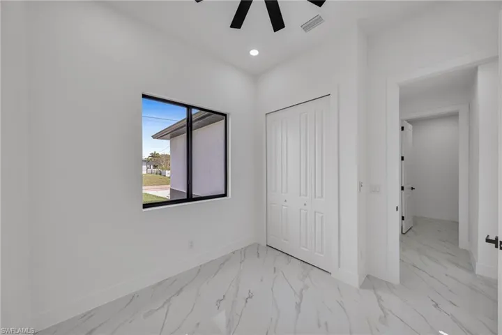 Unfurnished bedroom featuring light marble finish flooring, a closet, a ceiling fan, and recessed lighting